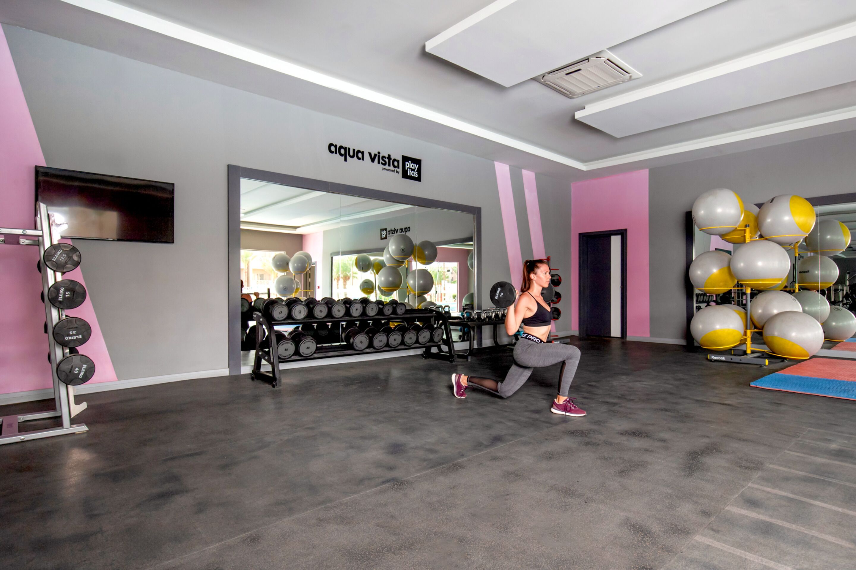 Une salle de sport équipée de matériel d’exercice, d’un miroir et d’un mur sur lequel est affiché un panneau.