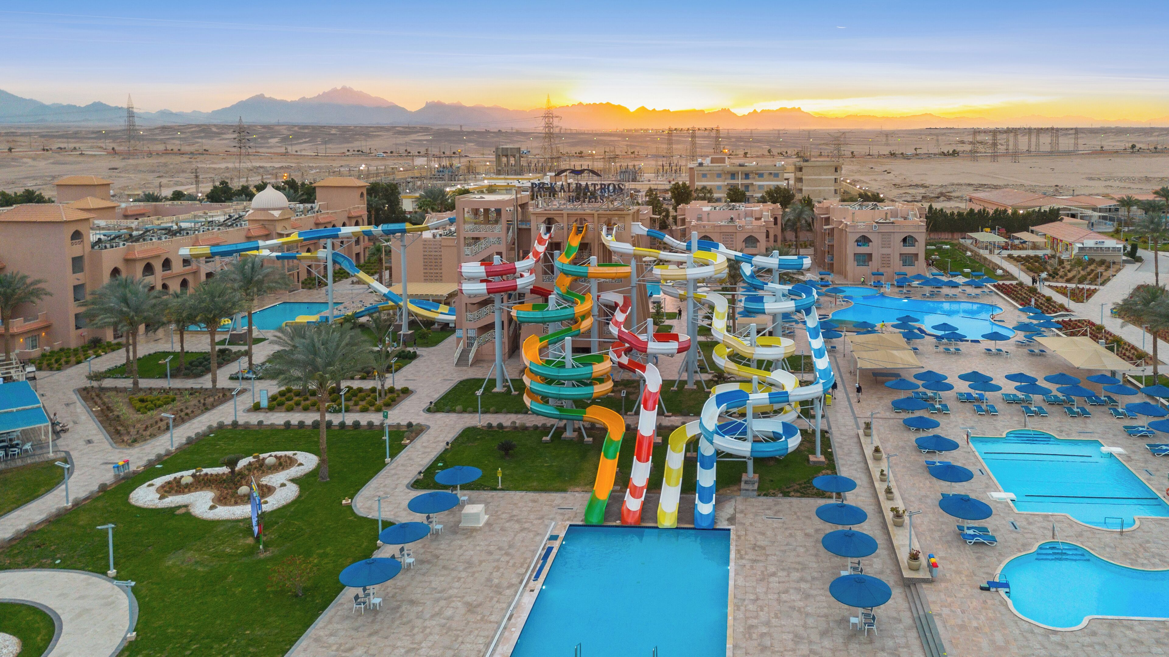 A hotel with multiple swimming pools, a water park, and a desert landscape in the background.