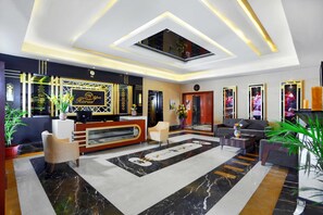 Un hall d’hôtel moderne avec un comptoir d’accueil, un espace salon et un grand miroir.