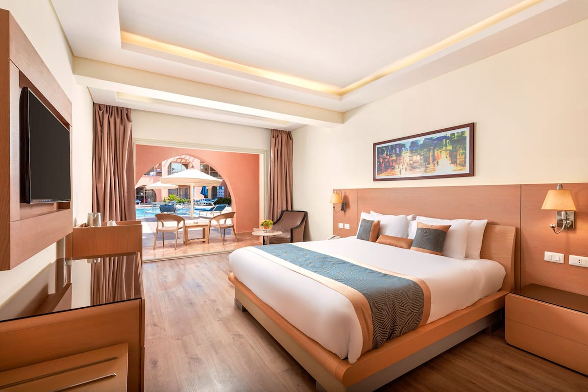 Een hotelkamer met een groot bed, een bureau, een stoel, een televisie en een schilderij aan de muur.