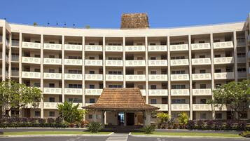 A multi-story hotel with a central entrance, balconies, and a distinctive roof design.