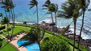 A resort with a swimming pool, palm trees, and a view of the ocean. - Royal Mauian - Maui Condo & Home (Kihei)