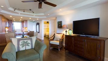 A spacious living area with a ceiling fan, a flat-screen TV, and a wooden cabinet.