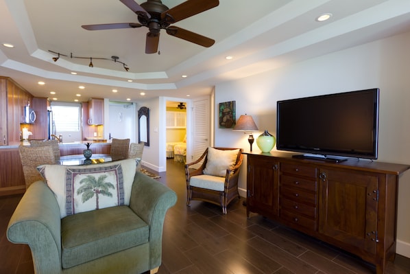 A spacious living area with a ceiling fan, a flat-screen TV, and a wooden cabinet.
