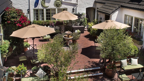 A courtyard with outdoor seating, potted plants, and a flag.