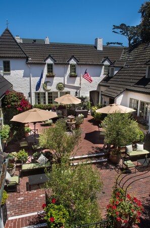 A courtyard with outdoor seating, potted plants, and a flag. - L Auberge Carmel (Carmel)
