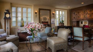 A traditional living room with a piano, a clock, and a floral arrangement.