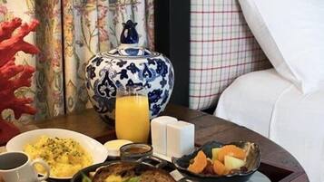 Een ontbijtplateau met eieren, toast, fruit en sap op een houten tafel.