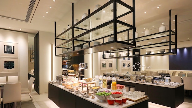 A modern kitchen with a central island stocked with various food items and a glass-fronted shelving unit above. - JinJiang Metropolo Hua Ting Guest House (Shanghai)