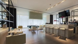 A modern hotel lobby with a bar area, seating arrangements, and a large TV screen. - JinJiang Metropolo Hua Ting Guest House (Shanghai)