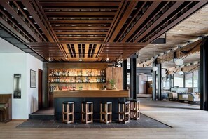 A modern bar area with wooden beams, a bar counter, and stools. - Hotel Boite (Borca di Cadore)