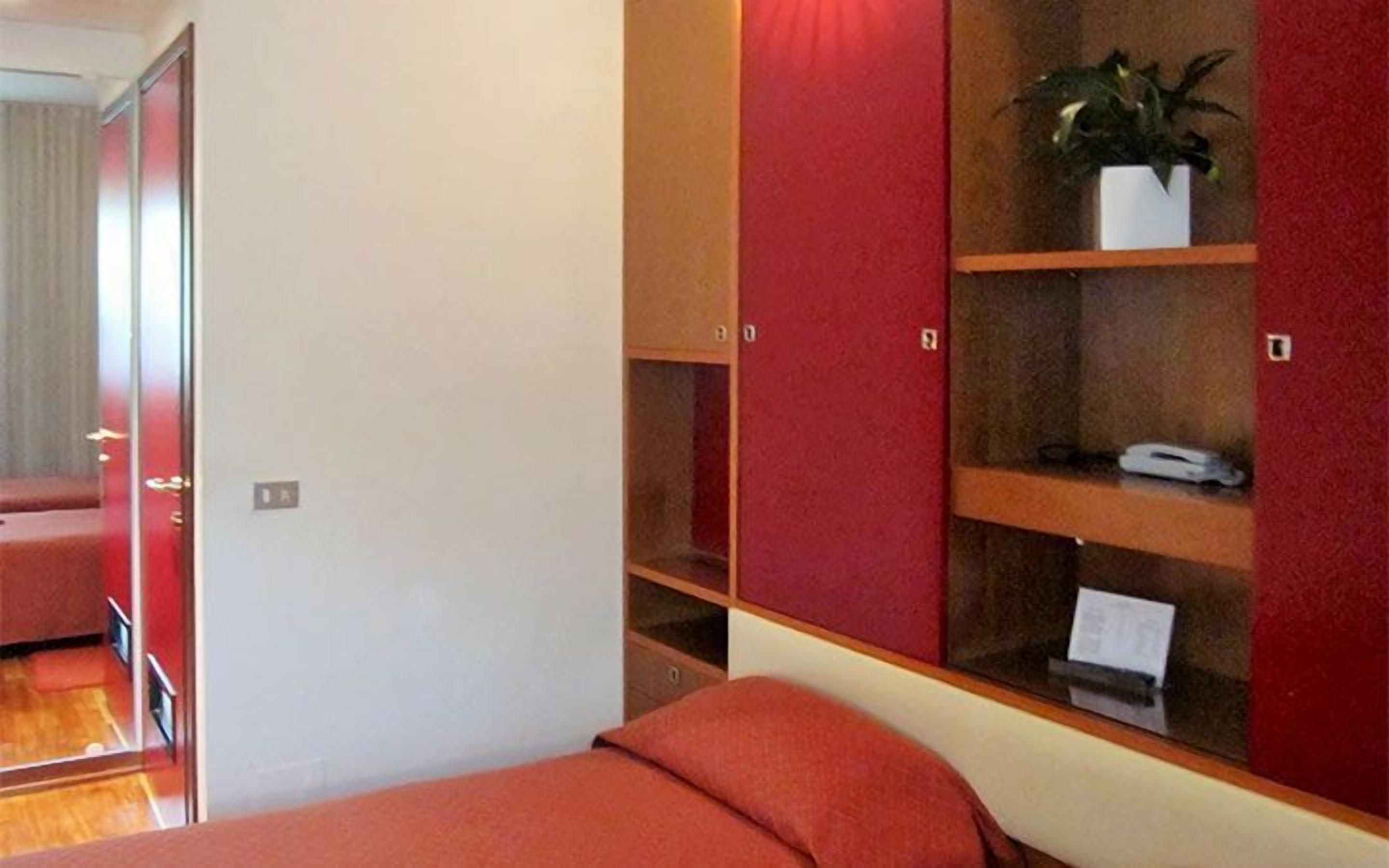 A bedroom with a bed, a wardrobe with shelves, and a mirror.
