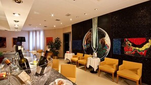 A modern hotel lobby with a bar area, seating, and artwork. - Grand Hotel President (Spilimbergo)