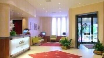 Un hall de hotel con mostrador de recepción, zona de estar y amplias ventanas.