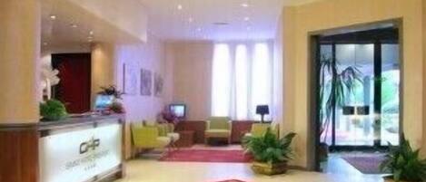 A hotel lobby with a reception desk, seating area, and large windows.