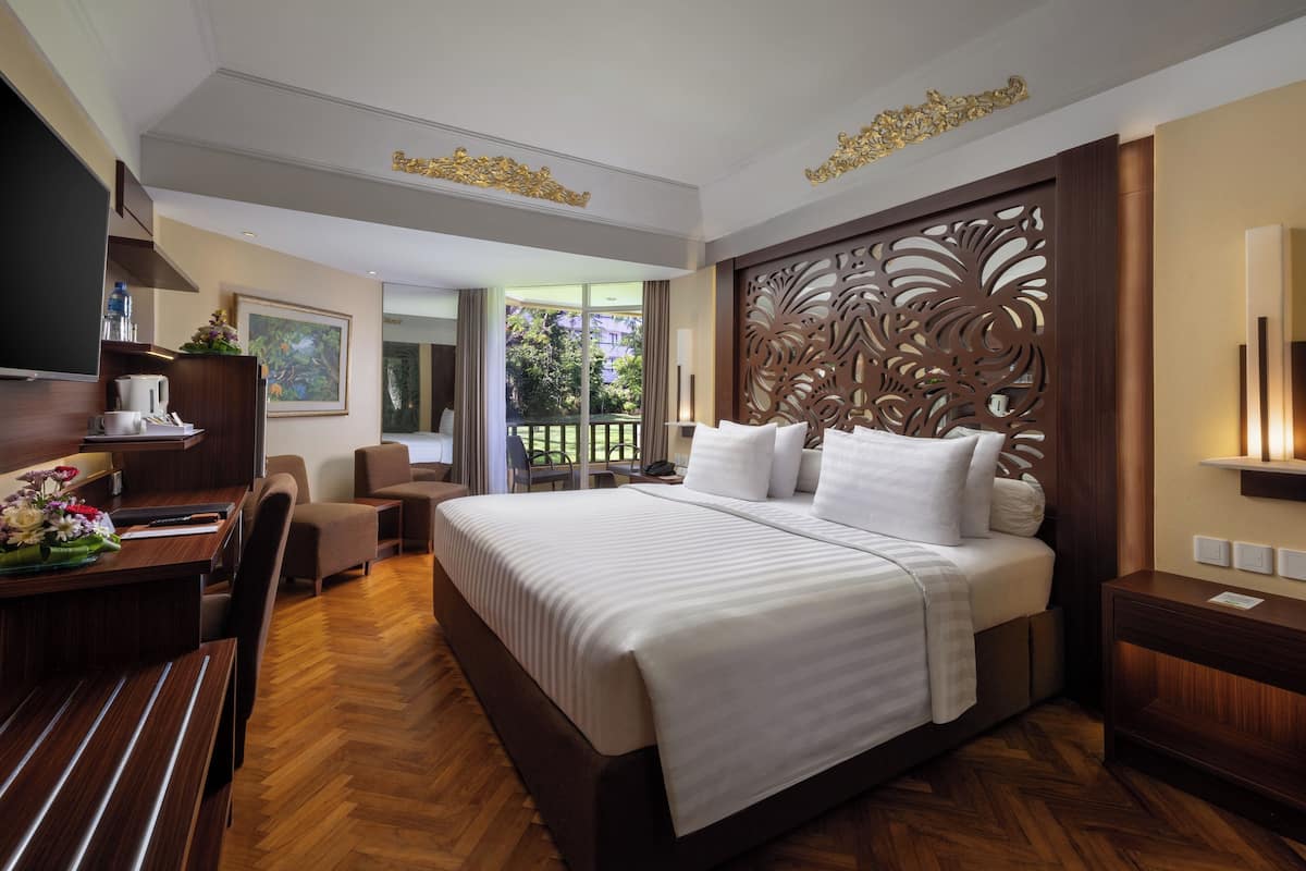 A hotel room with a large bed, wooden desk, and a television.