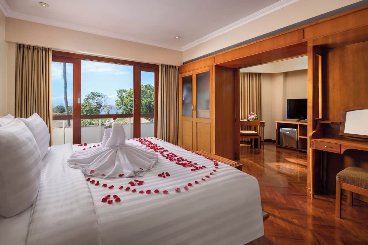 A hotel room with a large bed, a desk, a television, and a view of the outdoors.