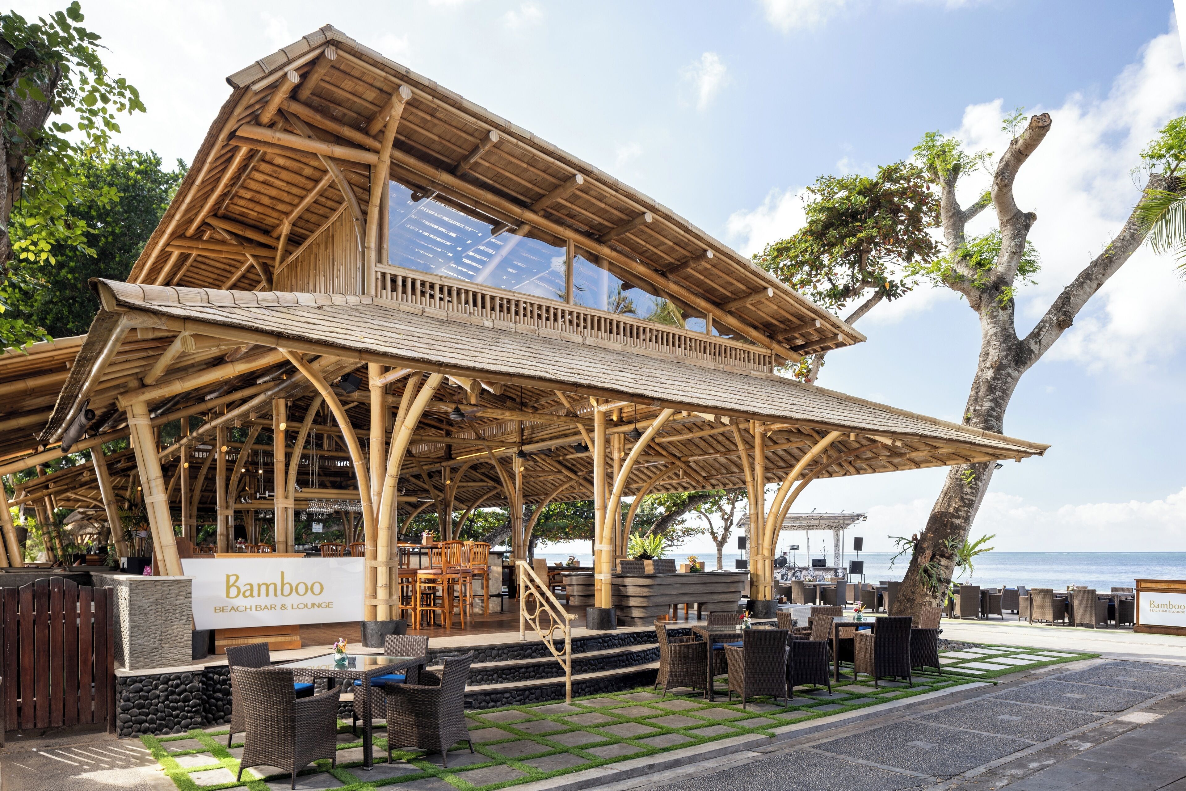 A bamboo-themed beach bar and lounge with outdoor seating and a view of the ocean.