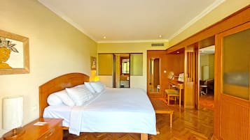 Una habitación de hotel con una cama grande, suelo de madera, un escritorio con una silla y un espejo.