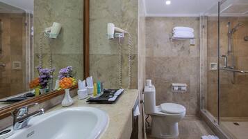A modern bathroom with a large sink, mirror, and glass-enclosed shower.
