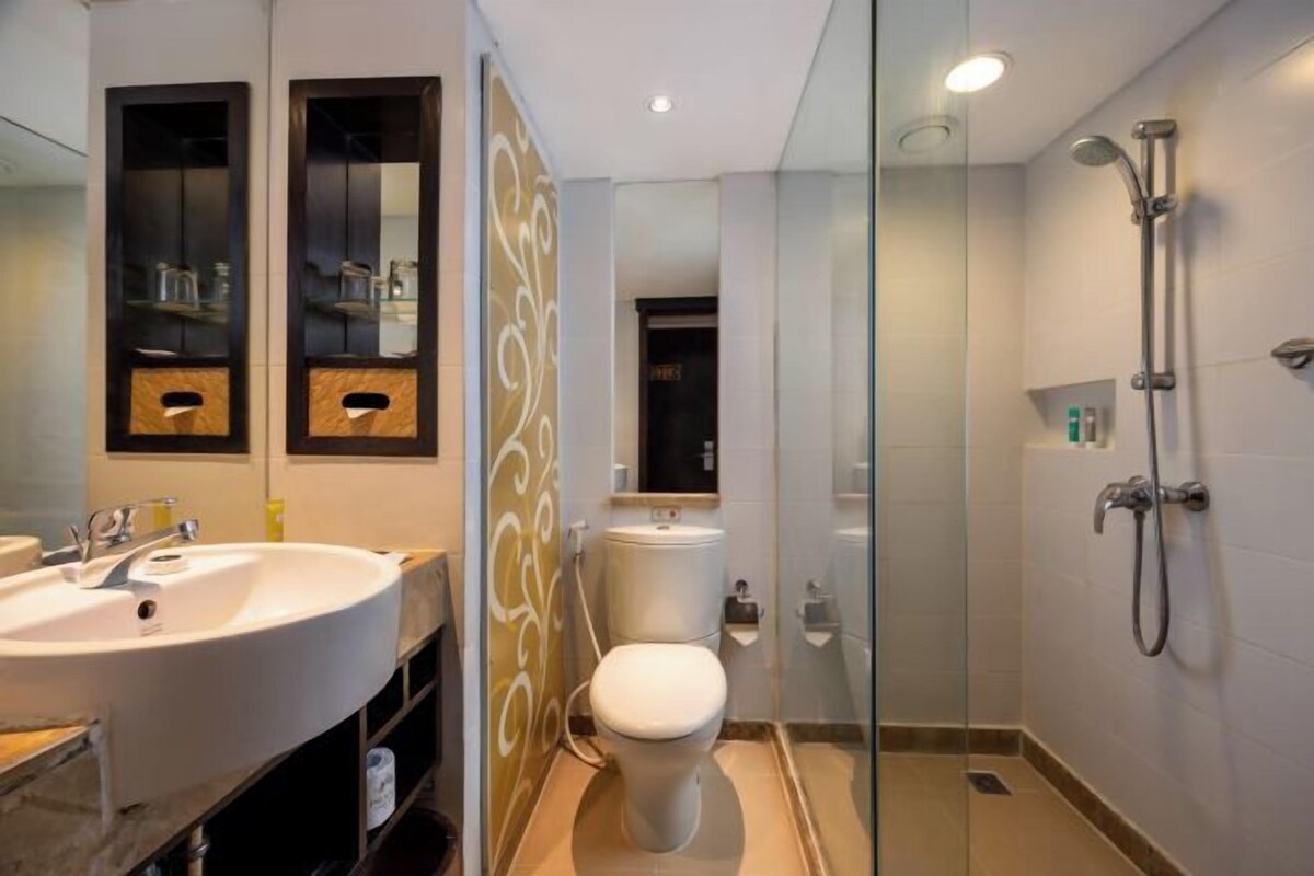 A modern bathroom with a glass-enclosed shower, a white sink, and a toilet.