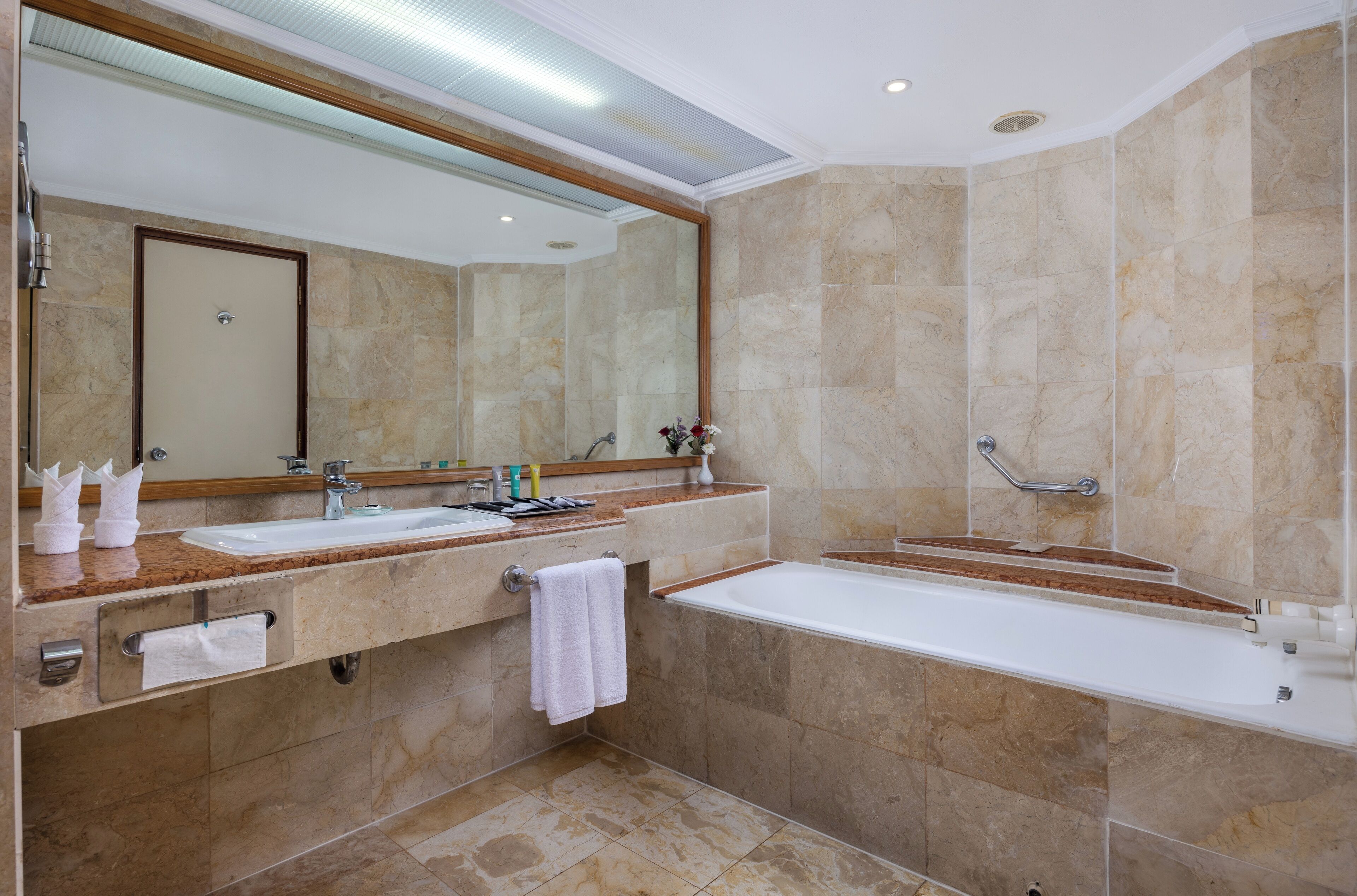 A modern bathroom with a double sink, a large mirror, a bathtub, and a shower area.