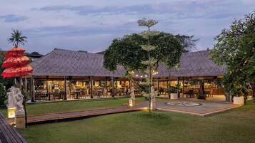 A restaurant with a thatched roof, outdoor seating, and a well-maintained garden.