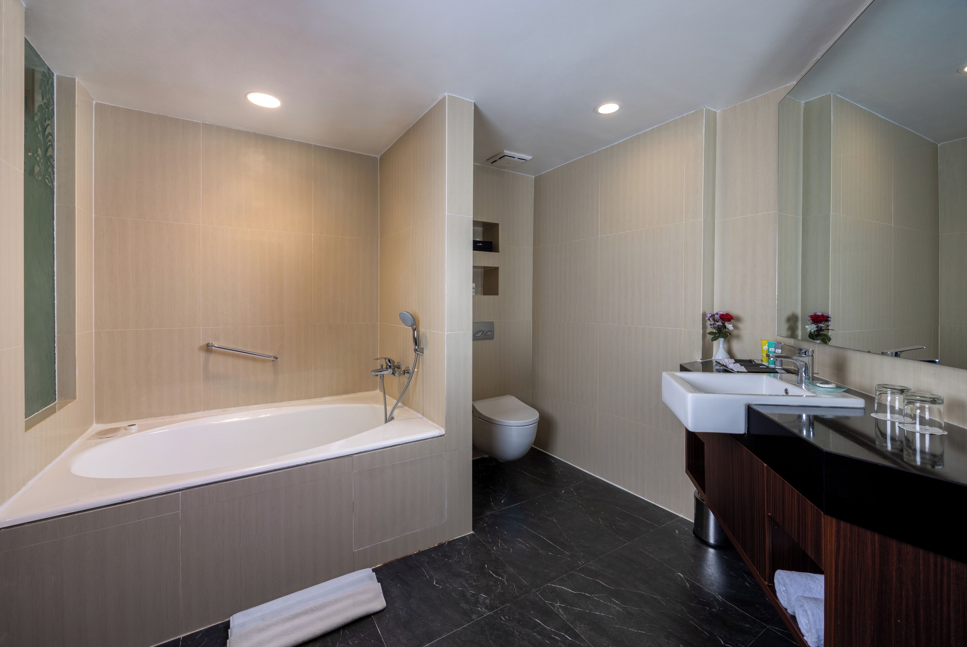 Un baño moderno con bañera, inodoro y tocador con espejo.