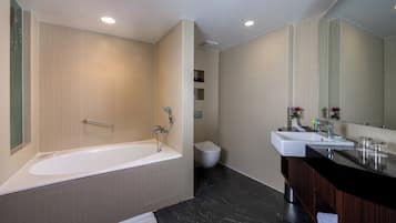 Un baño moderno con bañera, inodoro y tocador con espejo.