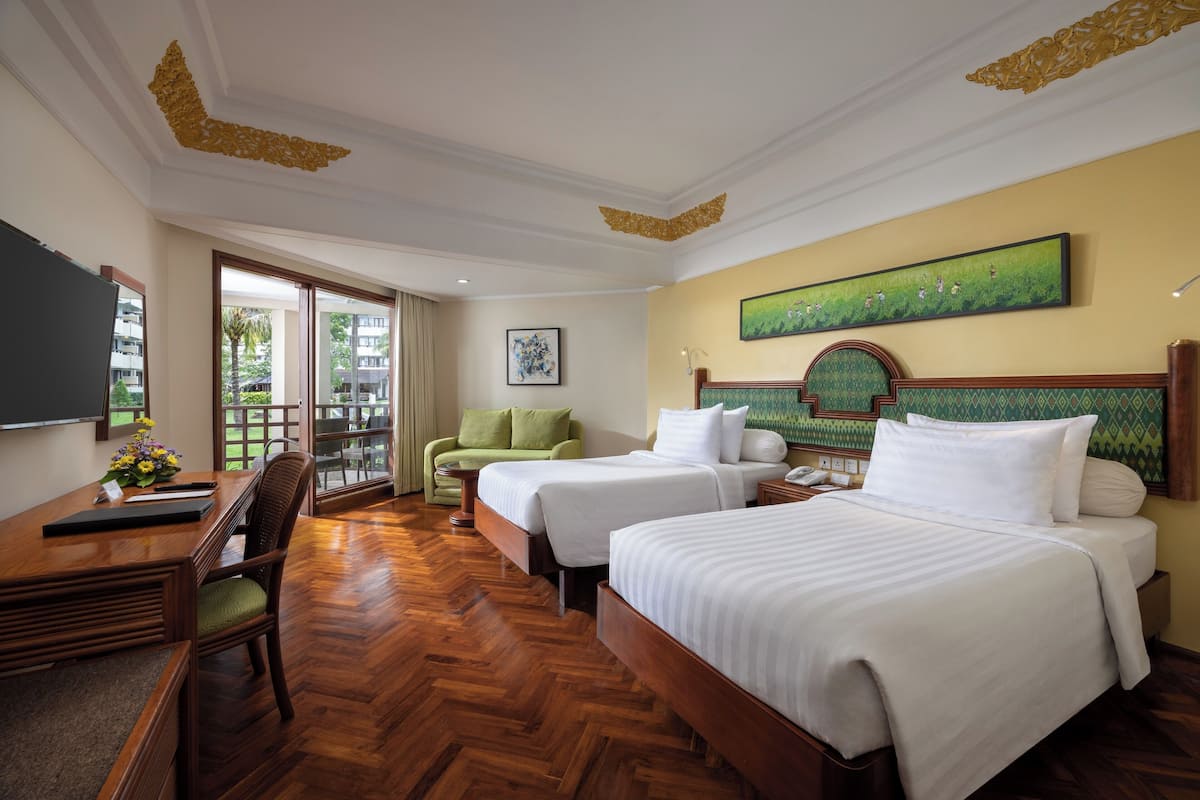 A hotel room with two beds, a desk, a chair, and a large window.