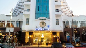 A hotel with a distinctive blue and white facade, multiple balconies, and a sign indicating it is managed by a company. - Dexon Roma Hotel & Aqua Park (Hurghada)