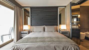 Una camera d'albergo moderna con un letto grande, comodini, uno specchio e vista sull'esterno.