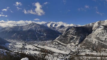 A mountainous landscape with snow-covered peaks and a valley with a town.