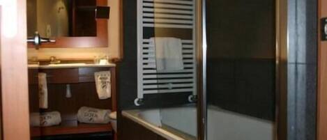 A bathroom with a wooden vanity, a mirror, a towel rack, and a window with blinds.