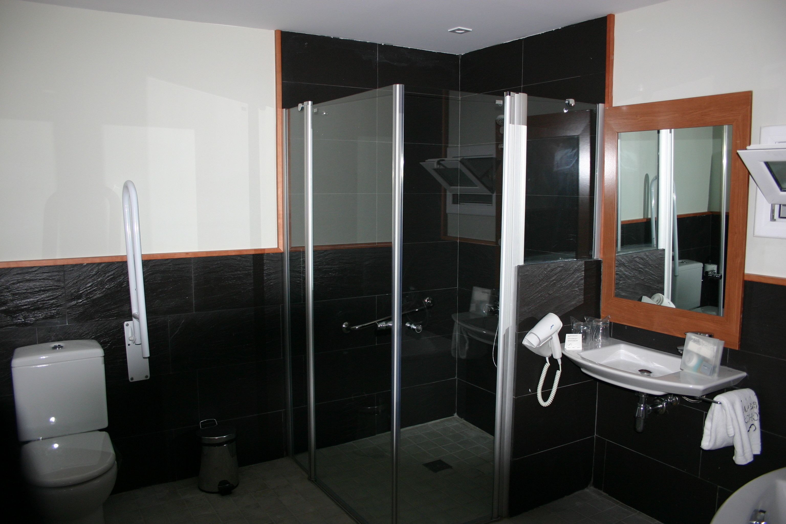 Une salle de bain moderne avec une douche à parois de verre, des toilettes et un lavabo surmonté d’un miroir.