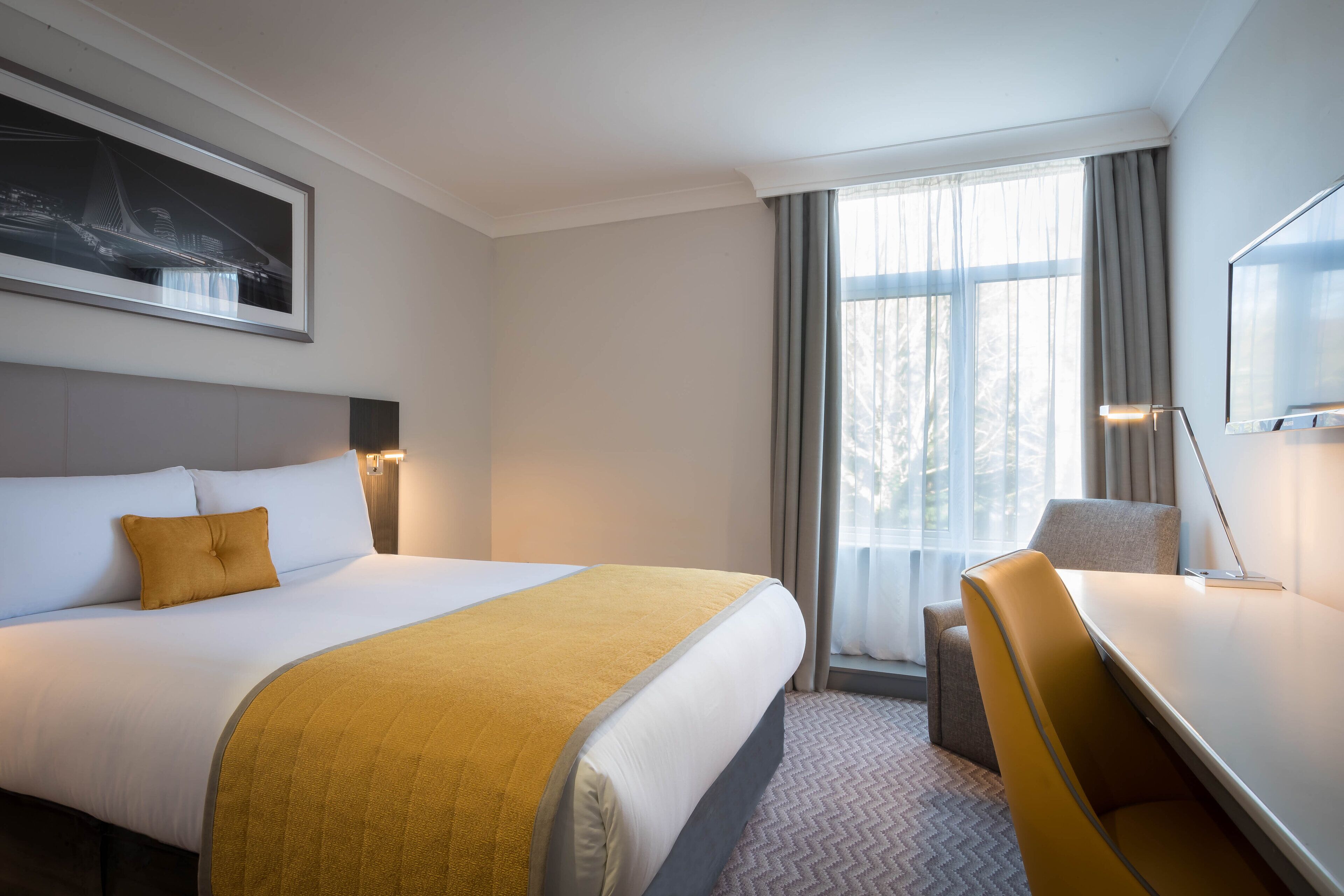 Una habitación de hotel con una cama grande, un escritorio y una silla.