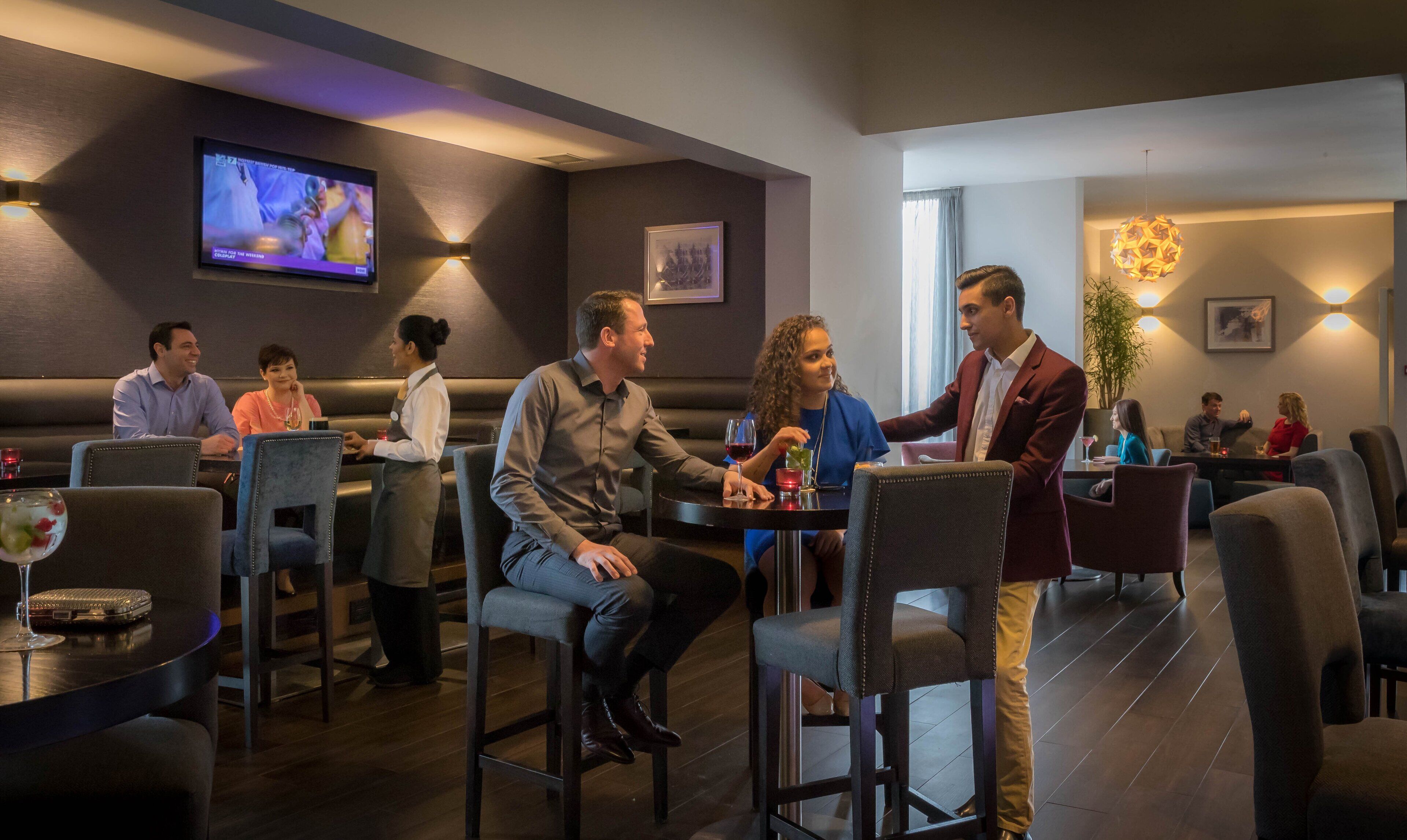 En restaurang med avskilda bås och bord, en tv-skärm och en servitör som tar hand om gästerna.