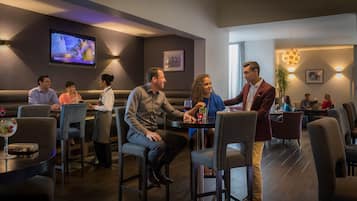 En restaurang med avskilda bås och bord, en tv-skärm och en servitör som tar hand om gästerna.