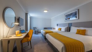 Een hotelkamer met twee bedden, een bureau met stoel, een televisie en een grote spiegel.