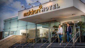 Een moderne hotelentree met glazen deuren, een trap en een bordje met de tekst 
