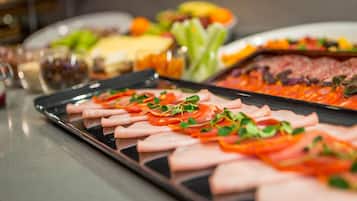 A buffet table with various food items including sliced meats, vegetables, and cheese.