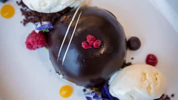 A dessert with chocolate and ice cream on a white plate with berries and chocolate shavings.