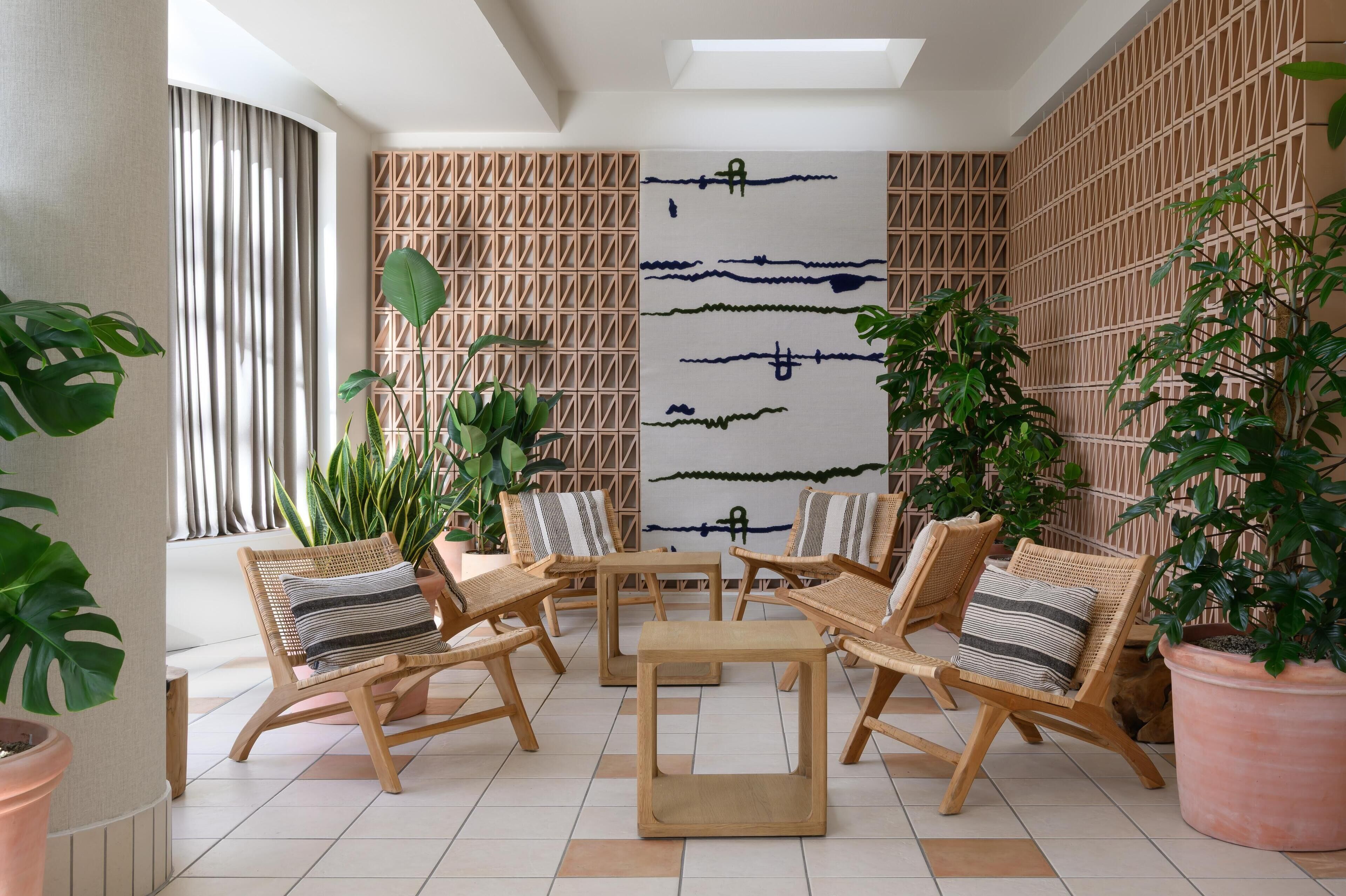 A sunlit patio area with wicker furniture, potted plants, and a decorative wall with geometric patterns.
