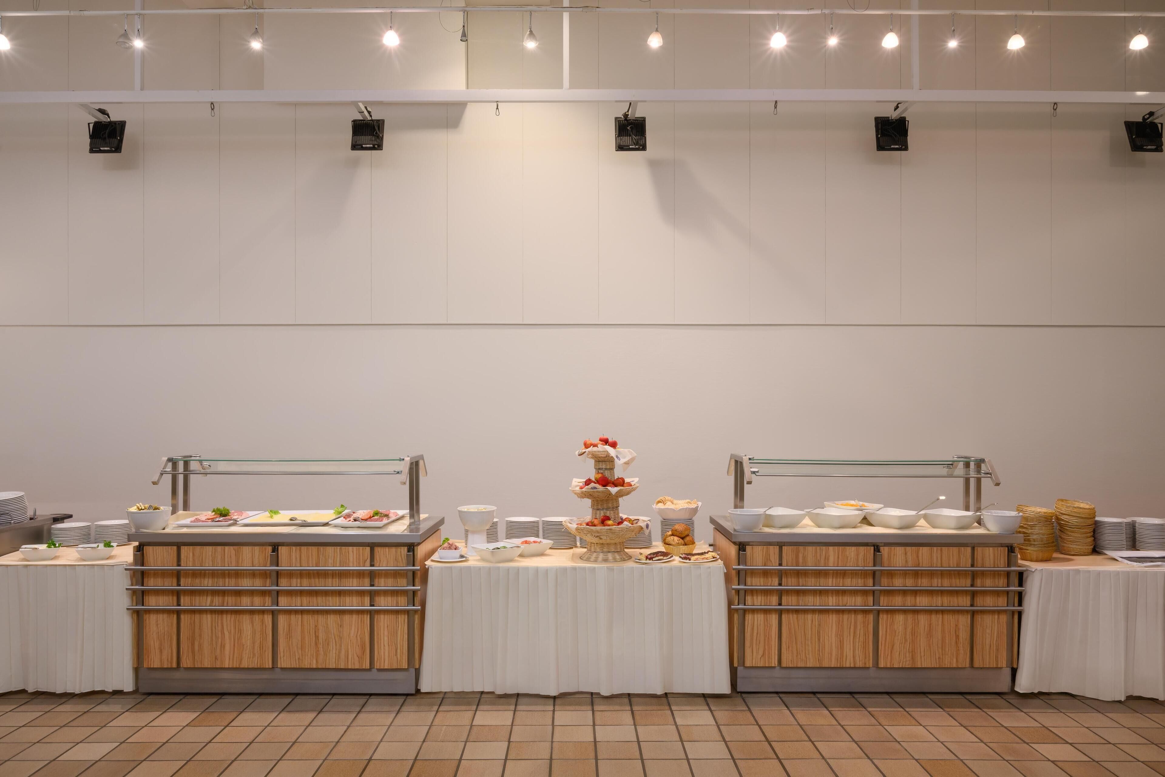 Un buffet organizzato con diverse postazioni di servizio, ognuna con varie pietanze e un'esposizione centrale a più livelli per i dolci.