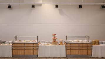 A buffet setup with multiple serving stations, each with a variety of food items and a central tiered dessert display.