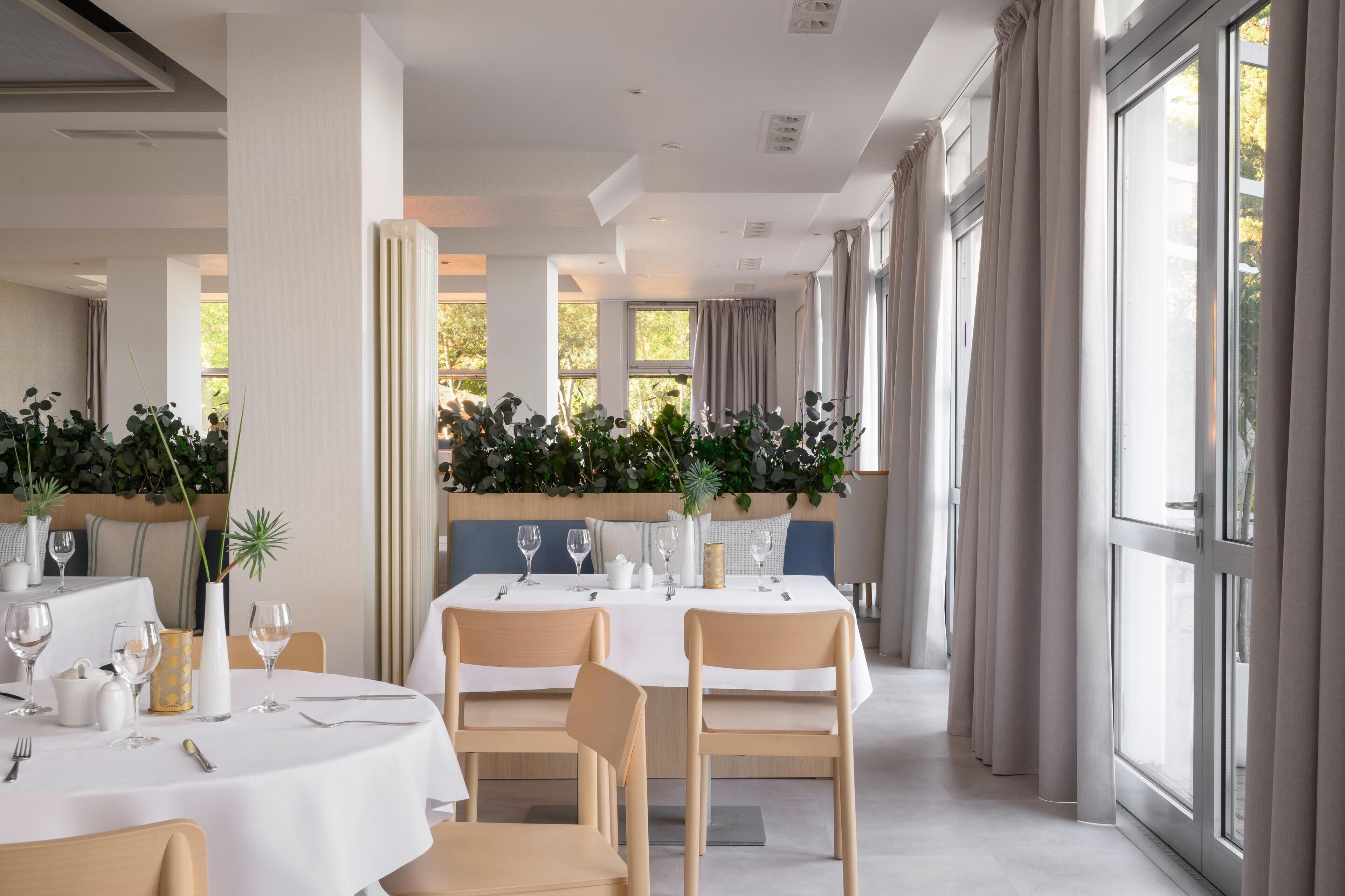 A modern dining area with round tables, chairs, and a long counter.