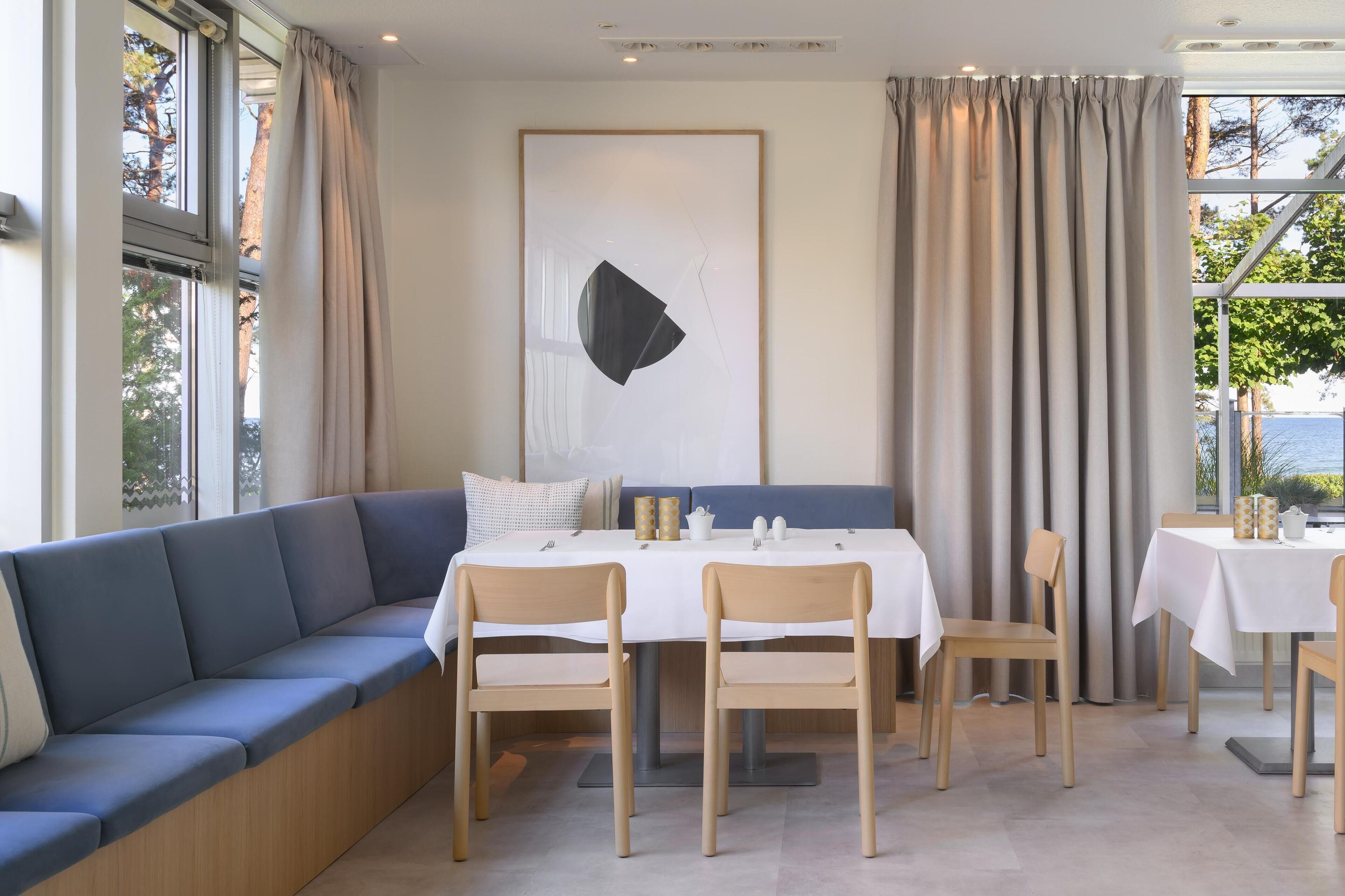 Un comedor moderno con un largo banco azul, sillas de madera y una mesa blanca.