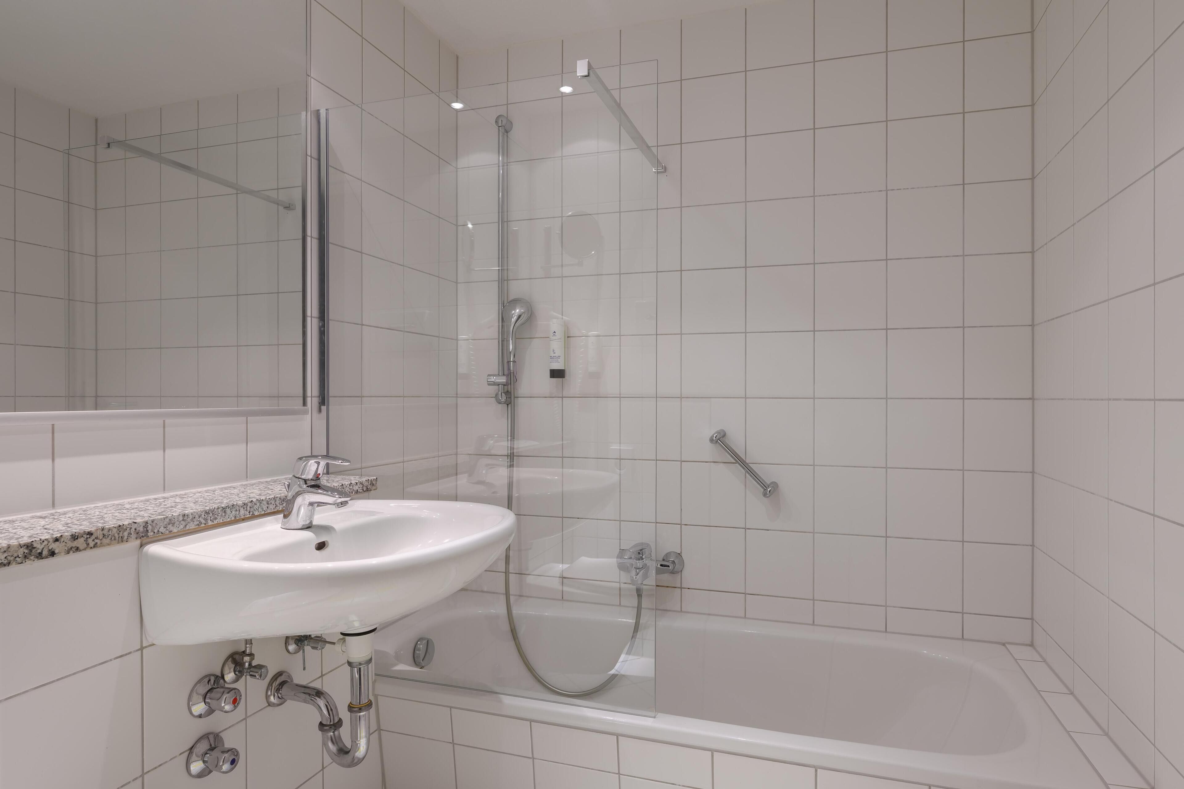 A modern bathroom with a glass-enclosed shower, a white sink, and a bathtub.