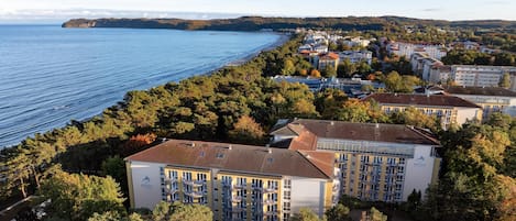 A coastal hotel with multiple floors, balconies, and a view of the sea.