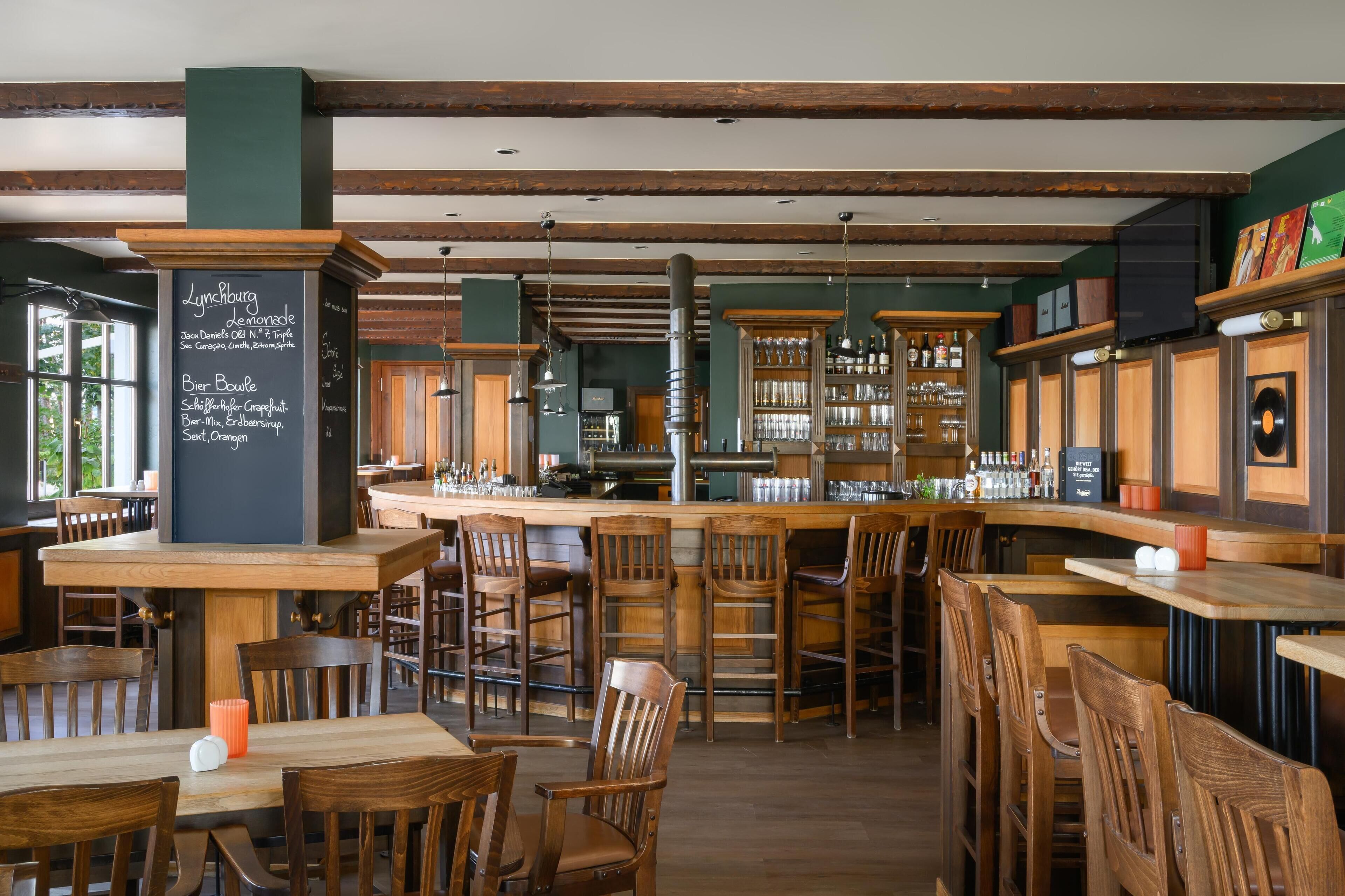 A cozy restaurant with wooden furniture, a chalkboard menu, and a bar area.